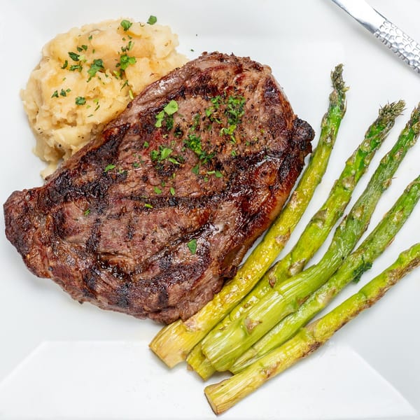 Grilled steak with mashed potatoes and asparagus on a white plate at Foster's on the Point.