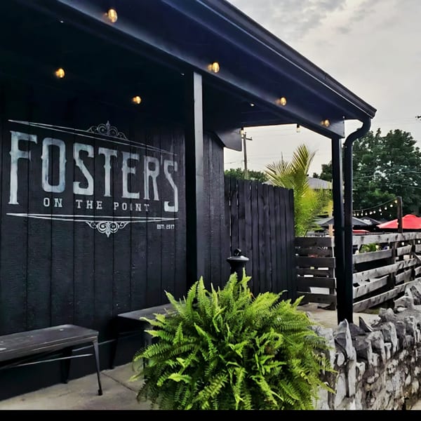 Foster's on the Point restaurant exterior with black siding, white sign, and green fern.